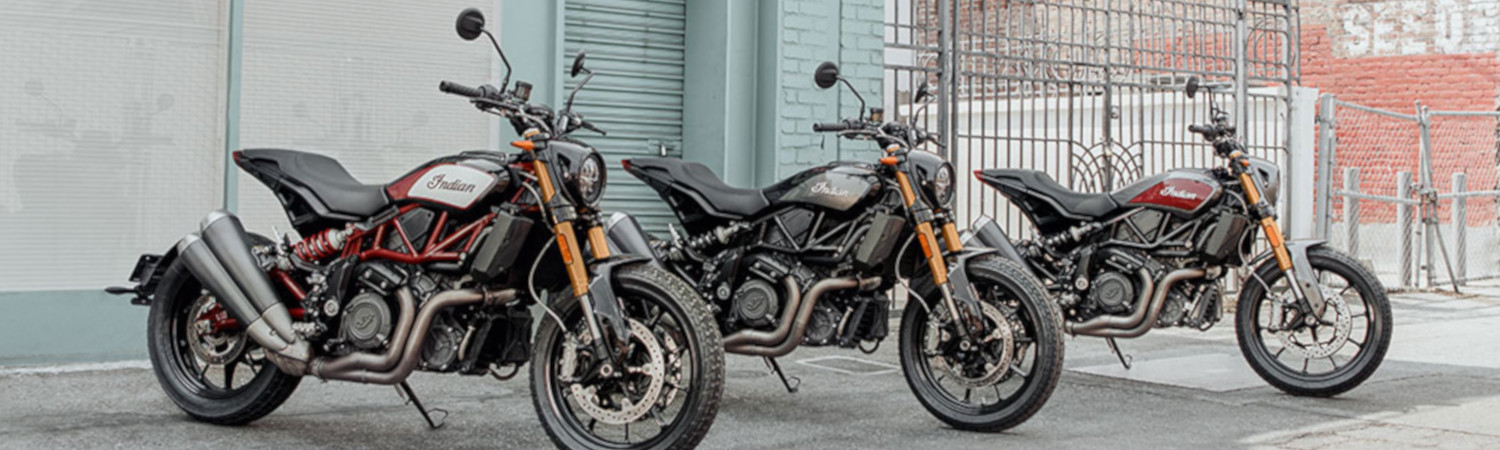 Three Indian FTR1200 motorcycles in front of a brick wall.